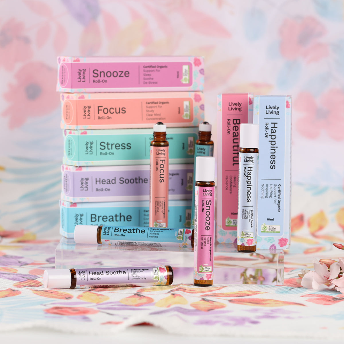Stacked roll-on boxes with Focus, Snooze, Happiness and Breathe roll-ons on a floral backdrop