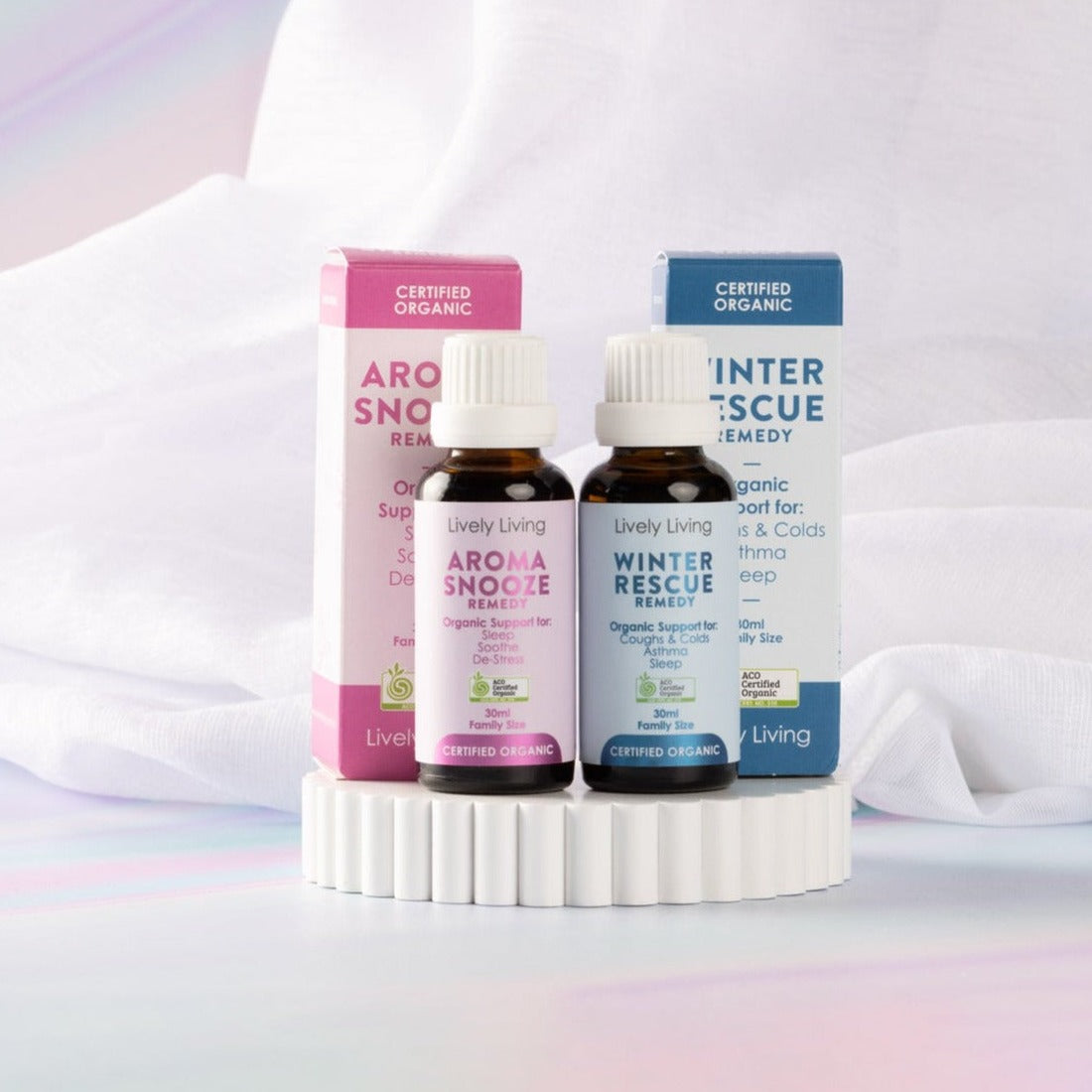 Aroma Snooze Remedy and Winter Rescue Remedy 30ml oils with boxes on a white scalloped pedestal