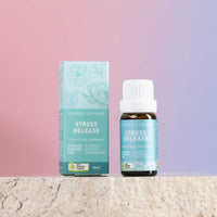 Lively Living Stress Release essential oil bottle and its matching light blue-green packaging box, displayed on a textured stone surface against a soft pink-to-purple gradient background.