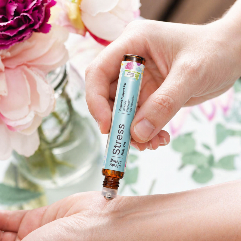 Hand holding a 'Stress Relief' rollerball with flowers in the background