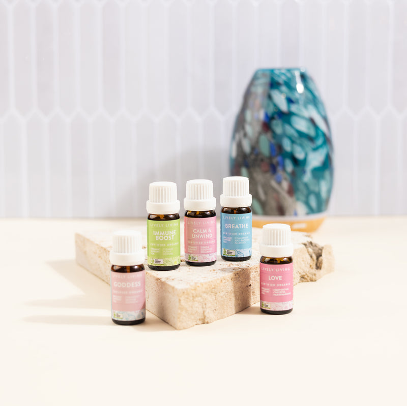 Set of essential oil bottles on a wooden block with a decorative vase in the background.