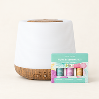 Aroma-Home diffuser with a ribbed white top and wood-look base beside the Lively Living Home Essentials Kit gift box of three oils
