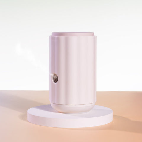 Aroma-Ascension Waterless diffuser. Pink cylindrical product on a white platform with a gradient background