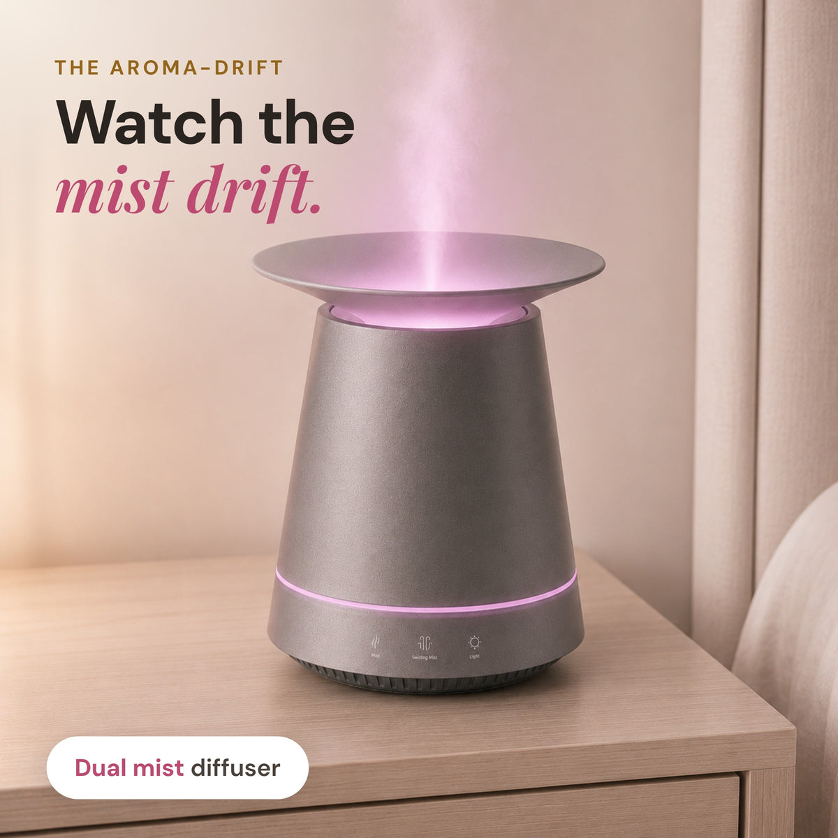Graphite Aroma-Drift Dual Mist Diffuser with a pink light ring releasing mist from its dish top on a timber bedside table, headline Watch the mist drift