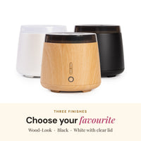 Aroma-Elm diffuser in its three finishes: wood-look, black, and white with a clear lid
