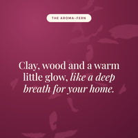 Aroma-Fern statement card in burgundy reading Clay, wood and a warm little glow, like a deep breath for your home.