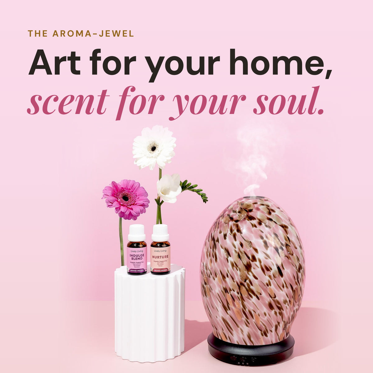 Aroma-Jewel Glass Diffuser with hand-painted pink, brown and gold speckles releasing mist beside two Lively Living oil bottles and pink flowers, headline Art for your home, scent for your soul
