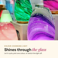 Aroma-Swirl glass diffusers glowing green, purple and pink, with the text Colour-changing light shines through the glass