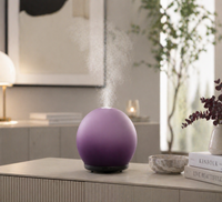 Purple spherical humidifier on a table with steam rising, in a home setting.