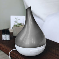 Gray and white diffuser on a wooden surface with a blurred background