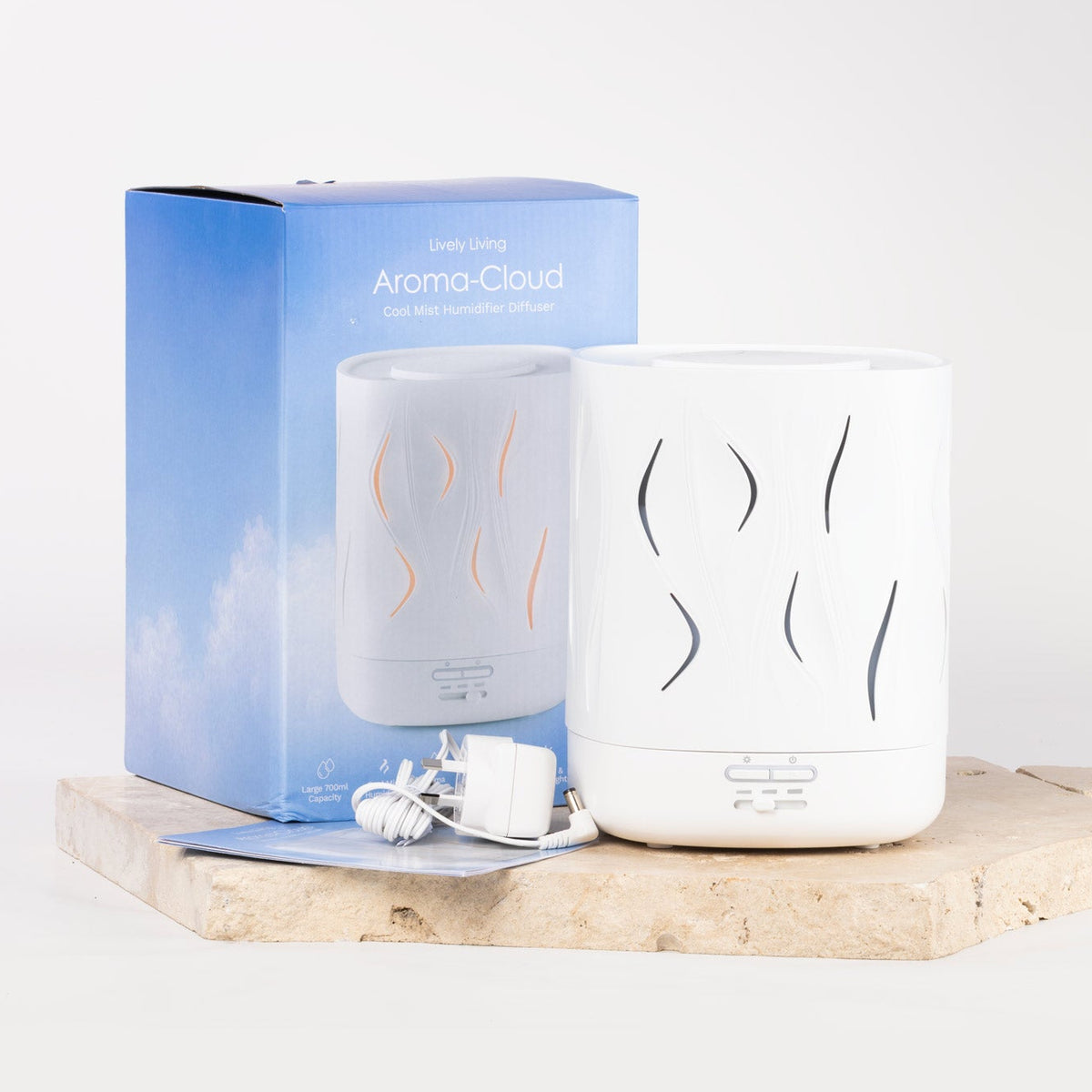 A white Aroma-Cloud diffuser shown next to its blue packaging box on a light stone slab, with a white charging cable and card in front.
