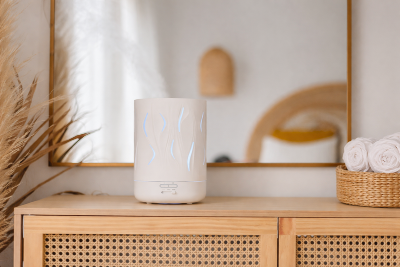 White ceramic diffuser on a wooden cabinet with decorative elements in the background