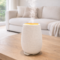 White ceramic diffuser on a wooden table with a living room background