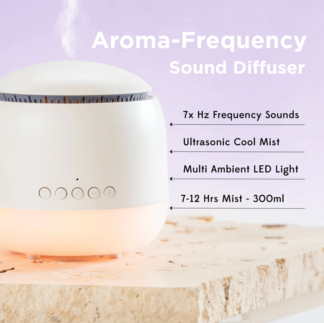 A white circular aroma-frequency sound diffuser with a glowing warm light base, shown on a stone slab with text listing features such as 7x Hz frequency sounds, ultrasonic cool mist, multi ambient LED light, and 7-12 hrs mist - 300ml.