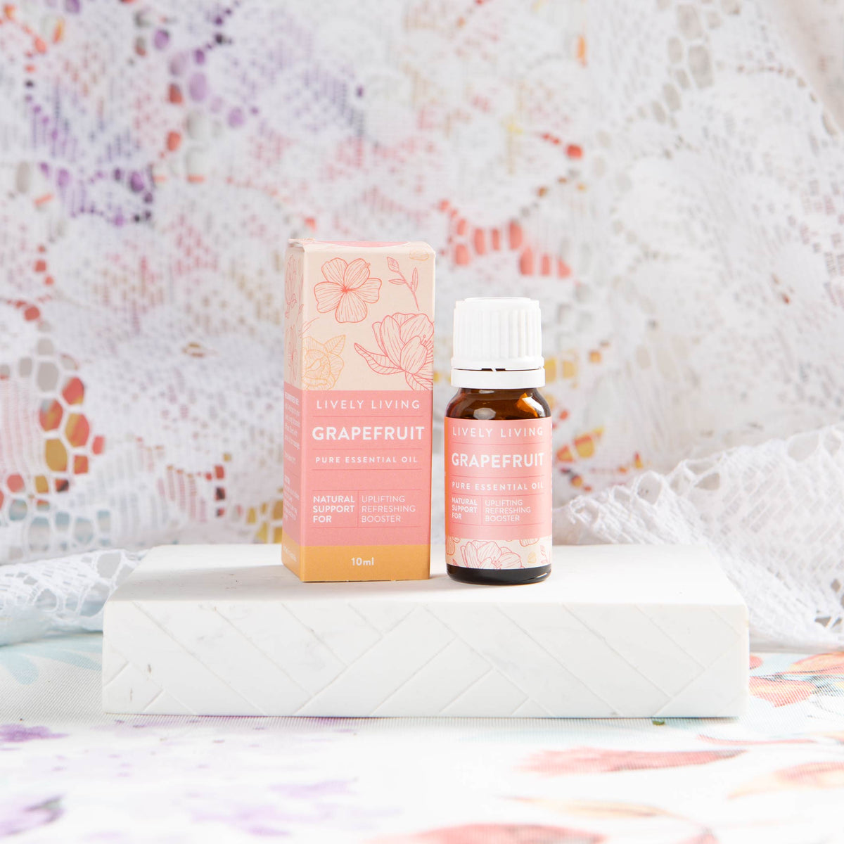 Lively Living essential "grapefruit" oil on a white brick with a lace background