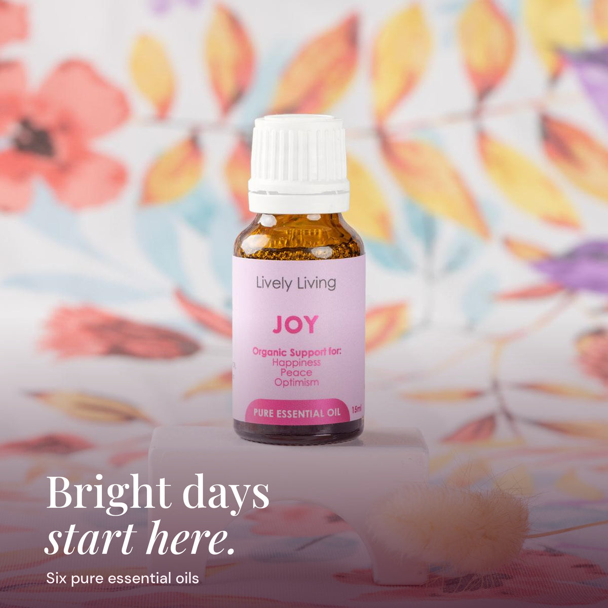Joy 15ml pure essential oil on a white stand with floral fabric: bright days start here