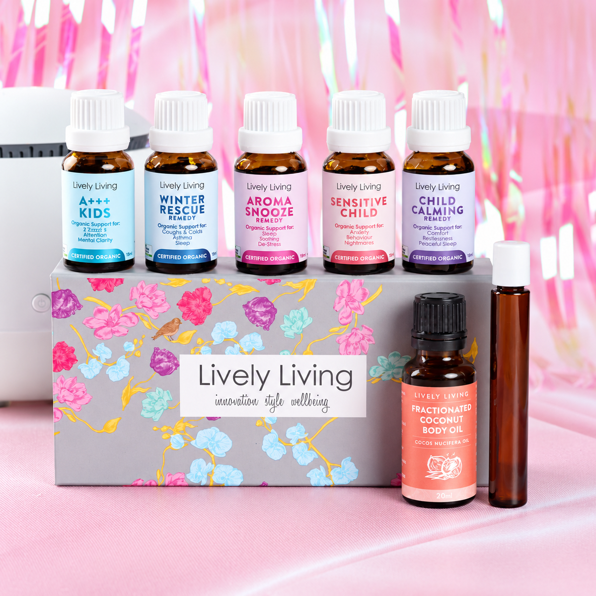 Lively Living Kids Certified Organic Essential Oil Kit: A++ Kids, Winter Rescue Remedy, Aroma Snooze, Sensitive Child and Child Calming 15ml oils on top of the floral gift box, with the 20ml coconut oil and roll-on bottle in front