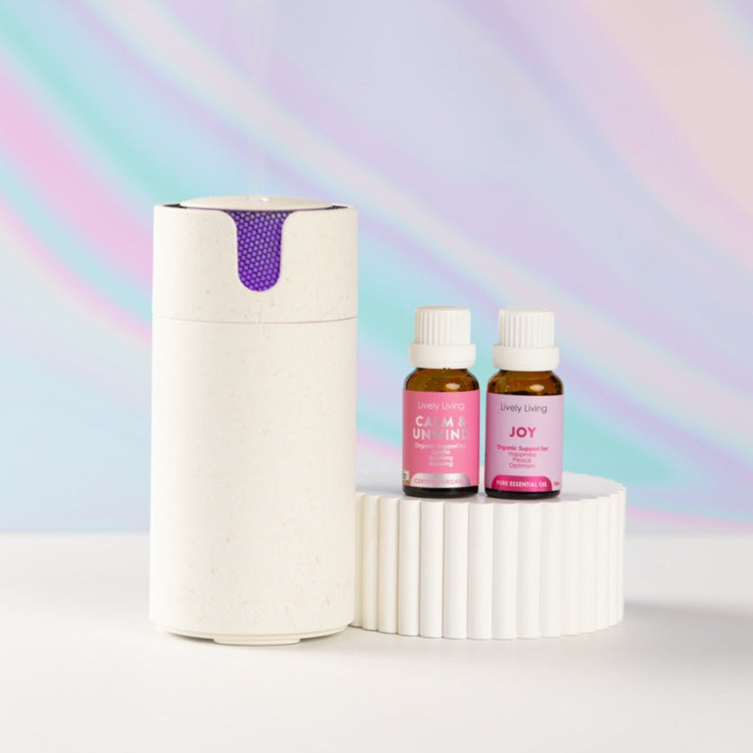 Stone Aroma-Recharge cordless diffuser beside Calm and Unwind and Joy oils on a white pedestal