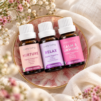 Lively Living Nurture, Relax and Calm & Unwind essential oil bottles on a pink floral dish with a gold rim, surrounded by small dried flowers and cream linen