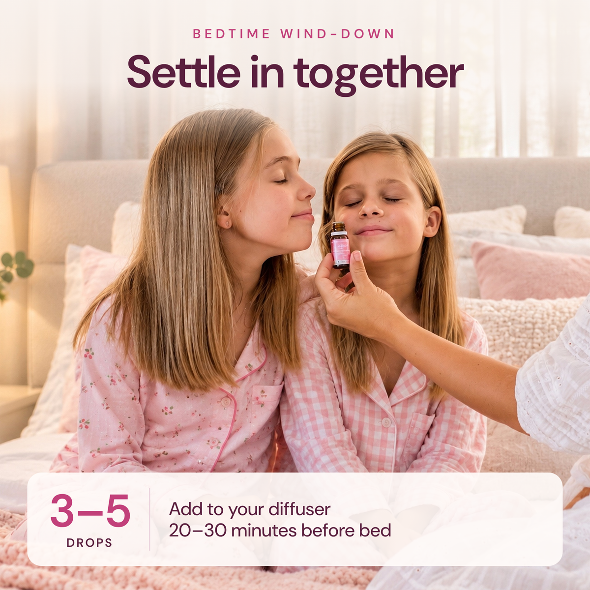 Two girls in pink pyjamas smelling Sensitive Child oil at bedtime, with the text Settle in together, 3 to 5 drops in your diffuser 20 to 30 minutes before bed