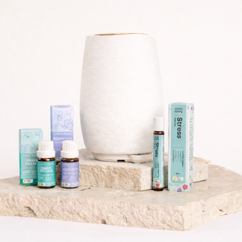 Collection of essential oil bottles and diffuser on a stone surface with a white background