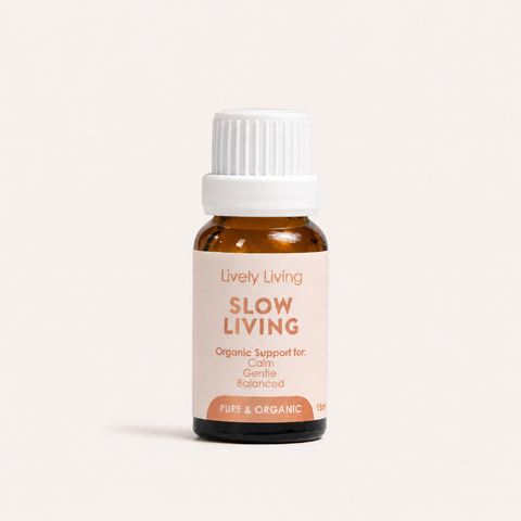 A small amber glass bottle with a white ribbed cap and a pale blush label reading 'Lively Living SLOW LIVING' on a clean off-white background.