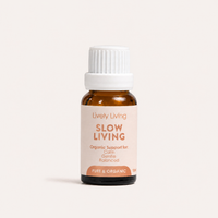 A small amber glass bottle with a white ribbed cap and a pale blush label reading 'Lively Living SLOW LIVING' on a clean off-white background.