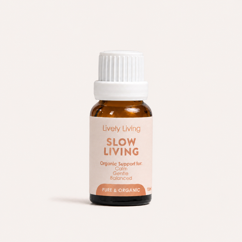 A small amber glass bottle with a white ribbed cap and a pale blush label reading 'Lively Living SLOW LIVING' on a clean off-white background.