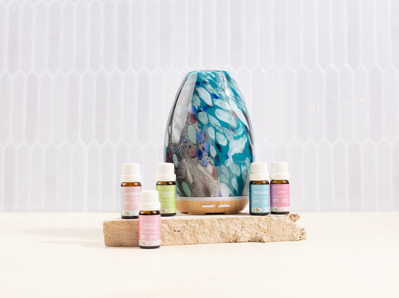 Aromatherapy diffuser with essential oil bottles on a wooden block against a white background