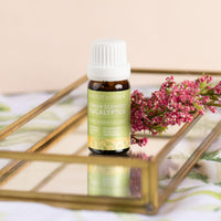 Lemon Scented Eucalyptus essential oil on a gold and glass tray with pink flowers