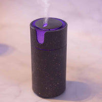 Charcoal speckled Aroma-Recharge cordless diffuser glowing purple and releasing mist