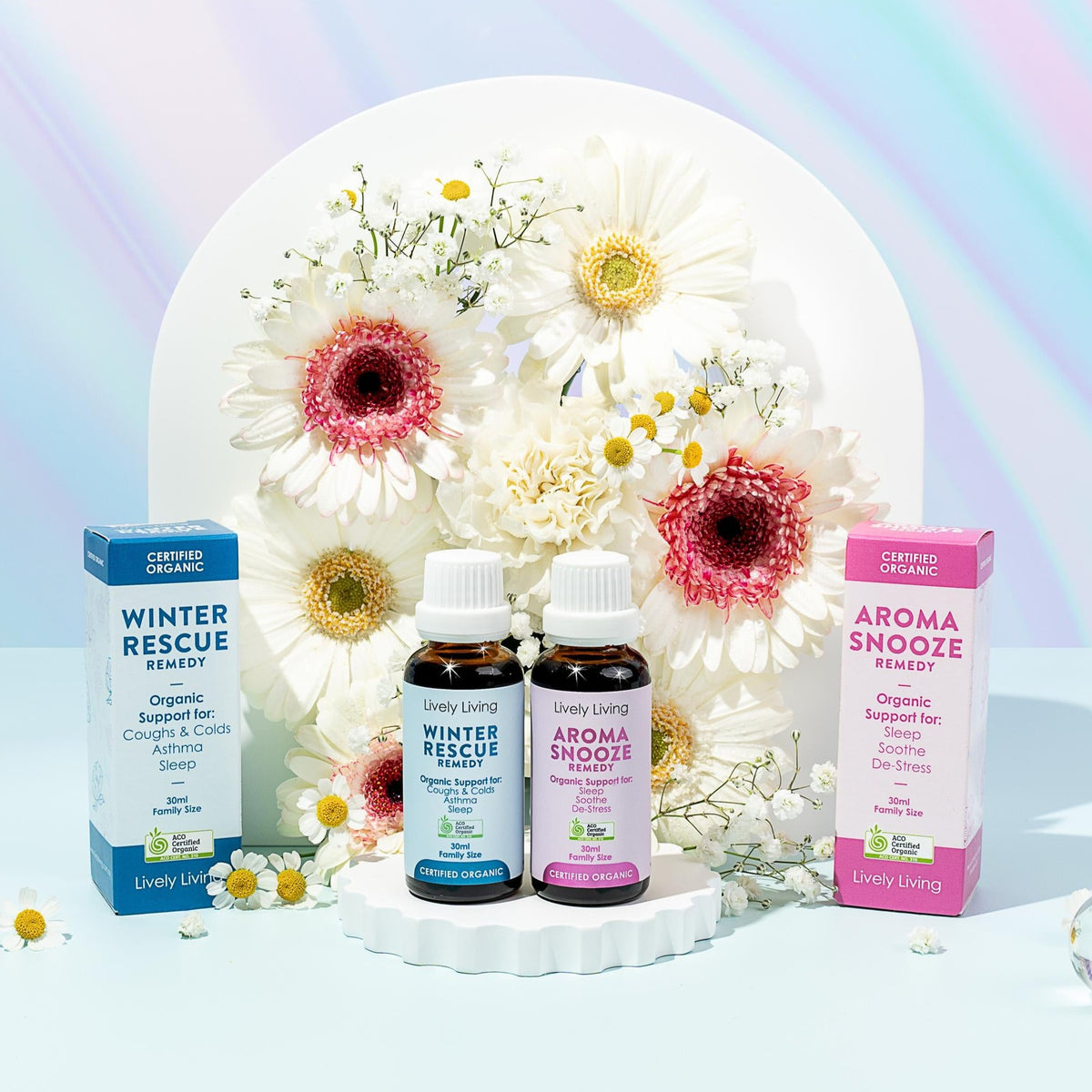 Winter Rescue Remedy and Aroma Snooze Remedy 30ml bottles and boxes on a white pedestal with daisies and gerberas