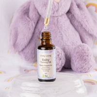 Dropper above an open bottle of Lively Living Baby Tummy Oil in front of a lilac plush bunny