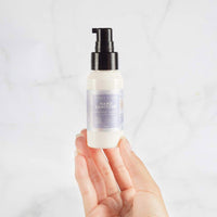 Hand holding the Lively Living Hand Sanitiser pump bottle against marble