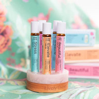 Stress, Elevate and Beautiful roll-ons in a marble stand with their boxes behind